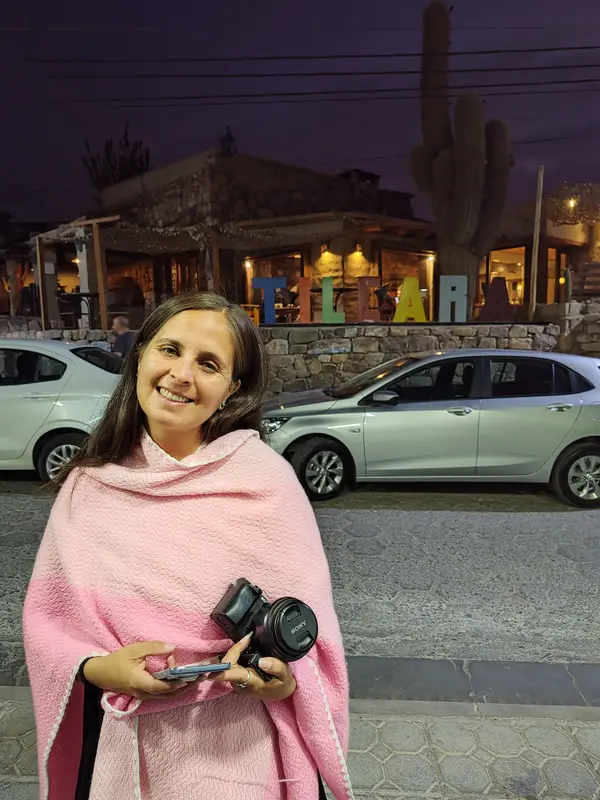 Andrea de noche, envuelta en un poncho rosa y con su cámara de fotos en la mano
