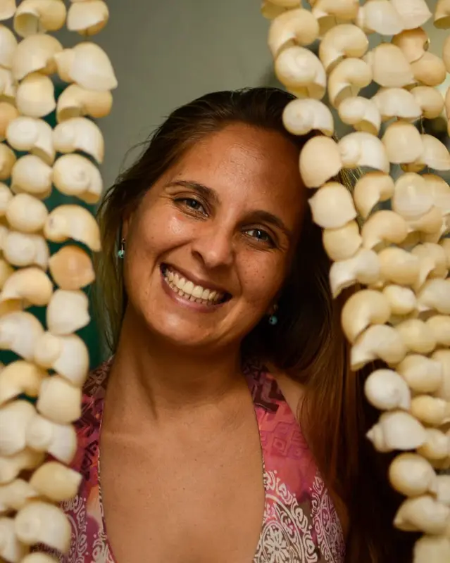 Andrea sonriendo entre dos cortinas de caracoles blancos colgantes