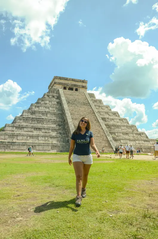 Andrea caminando sobre el césped frente a la pirámide de Chichén Itzá, en México