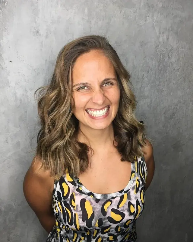 Retrato de Andrea sonriendo ampliamente frente a una pared gris, con una musculosa de estampa animal