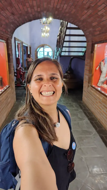 Andrea sonriendo en una selfie con mochila en un pasillo abovedado de ladrillo